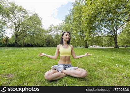 Full length of beautiful fit woman performing yoga at park