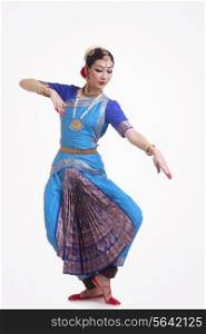 Full length of beautiful woman performing Indian Bharat Natyam dance on white background