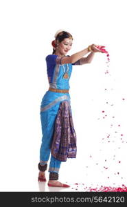 Full length of Bharatanatyam dancer dropping rose petals on white background