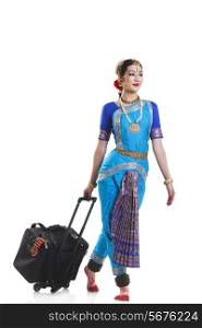 Full length of Bharatanatyam dancer with luggage walking over white background