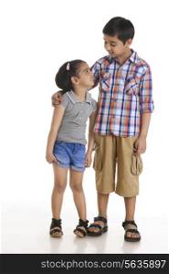 Full length of brother and sister looking at each other against white background