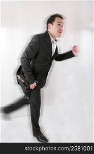 Full length of business man with briefcase running on white background