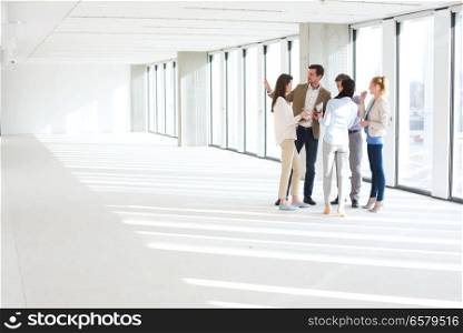 Full length of business people having discussion in empty office space