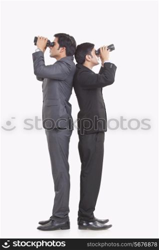Full length of businessmen looking through binoculars against white background