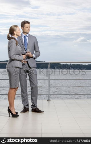 Full length of businesspeople holding wineglasses on terrace