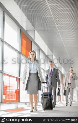 Full length of businesspeople with luggage walking in railroad station