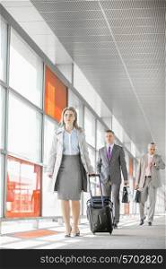 Full length of businesspeople with luggage walking in railroad station