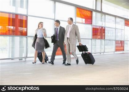 Full length of businesspeople with luggage walking on railroad platform