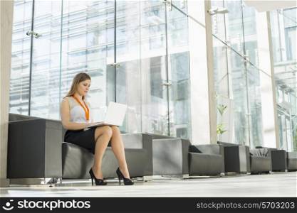 Full-length of businesswoman using laptop at office lobby