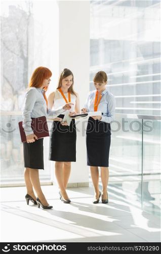 Full-length of businesswomen discussing over documents in office