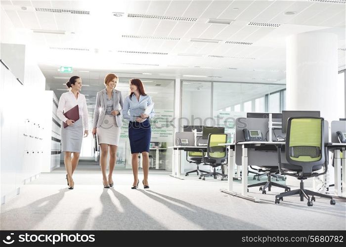 Full-length of businesswomen with file folders walking in office