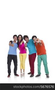 Full length of cheerful young friends pointing at you over white background