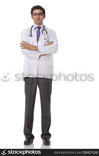 Full length of confident young doctor with hands folded over white background