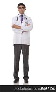 Full length of confident young doctor with hands folded over white background
