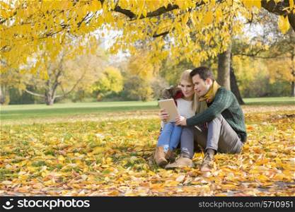 Full length of couple using tablet PC in park during autumn