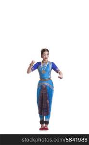 Full length of dancer gesturing while performing Bharatanatyam against white background