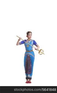Full length of dancer holding trident while performing Bharatanatyam against white background