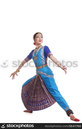 Full length of dancer in traditional wear performing Bharatanatyam against white background