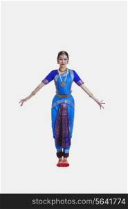 Full length of dancer in traditional wear performing Bharatanatyam against white background