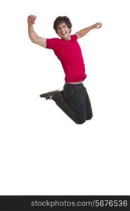 Full length of excited young man jumping with arms raised over white background
