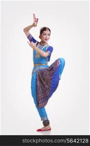 Full length of female Bharat Natyam dancer performing over white background