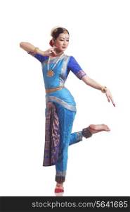 Full length of female classical dancer performing Bharatanatyam on white background
