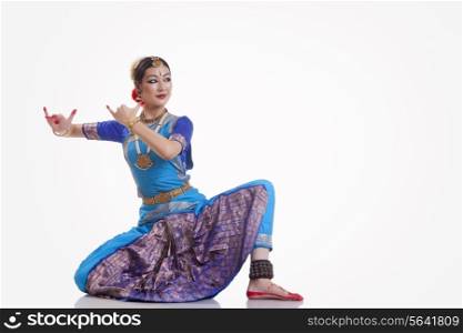 Full length of female dancer performing Bharatanatyam against white background