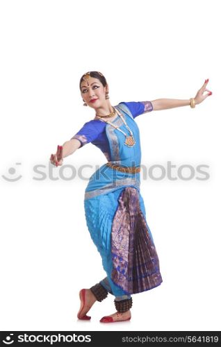 Full length of female dancer performing Bharatanatyam against white background