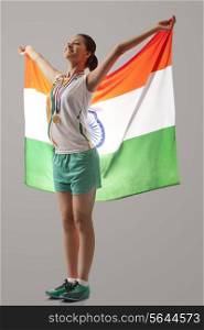 Full length of female medalist celebrating victory with Indian flag isolated over gray background