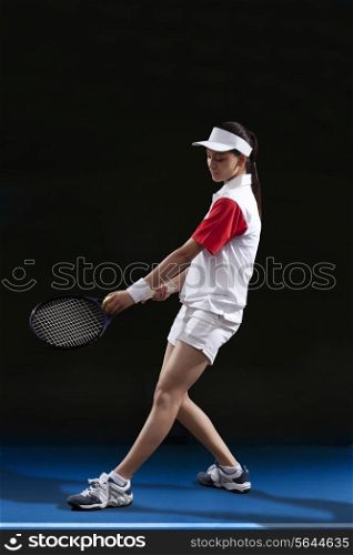 Full length of female tennis player preparing to serve at court