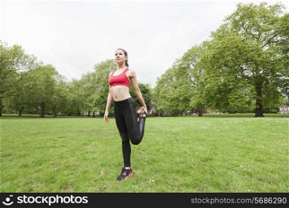 Full length of fit young woman performing stretching exercise in park