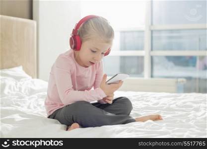 Full length of girl listening music on headphones in bedroom
