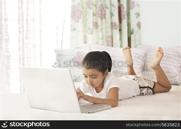 Full length of girl using laptop in bed