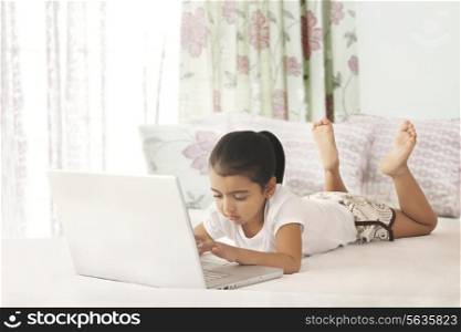 Full length of girl using laptop in bed