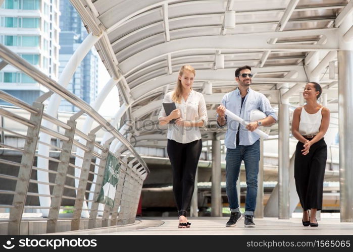 Full Length Of Happy Business People Talking While Walking On Walkway Bridge In City