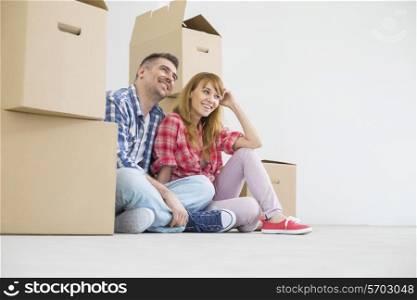 Full-length of happy couple sitting in new house