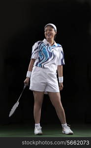 Full length of happy female player holding badminton racket isolated over black background