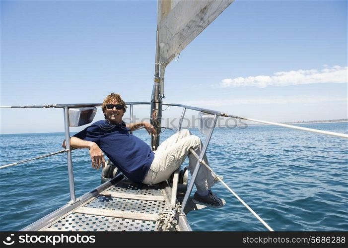 Full-length of happy man sitting on bow of yacht