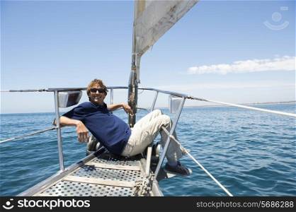 Full-length of happy man sitting on bow of yacht