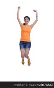 Full length of happy young woman jumping with arms raised over white background
