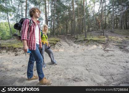 Full length of hiking couple walking in forest
