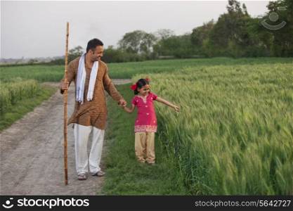 Full length of little girl with her father in a wheat field