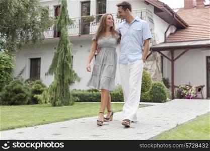 Full length of loving young couple walking on footpath in park