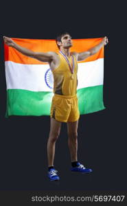 Full length of male medalist with Indian flag looking up over black background