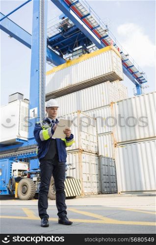 Full-length of male supervisor writing on clipboard in shipping yard