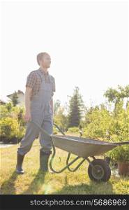 Full-length of man pushing wheelbarrow at garden