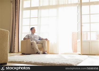 Full length of man relaxing on armchair at home