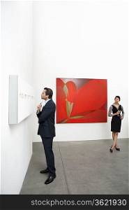Full length of man standing in front of wall painting and woman