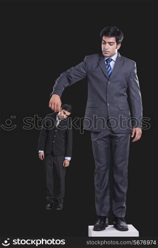 Full length of manager holding businessman by collar against black background