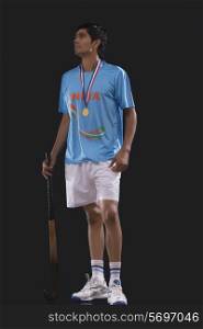 Full length of medalist with hockey stick looking up over black background